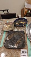 Three metal decorative plates placed on a countertop showing different shapes and finishes.