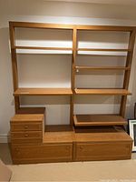 Front view of the wood shelving unit showing adjustable shelves and four drawers.