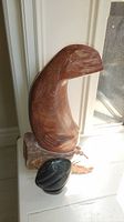 Full view of red-toned polished stone bird sculpture on base near window with natural light