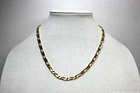 Front view of gold tone Figaro link necklace displayed on a white mannequin bust.