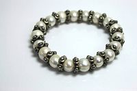 Full view of the elastic pearl bracelet showing arrangement of pearls and silver rose beads.