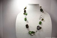 Front view of the three strand necklace displaying the green and clear glass beads on silver tone wire.