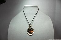 Full view of the Kenneth Cole Reaction necklace on a display bust, showing the cord, metallic bead, and round pendant.
