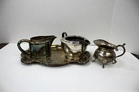 Full view of three creamers and a tray showing their relative sizes and decorative details.