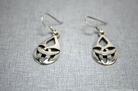 Front view of the pair of sterling silver Celtic knot earrings on a grey fabric background.