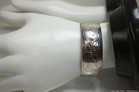 Silver open cuff bracelet on display hand showing etched design.