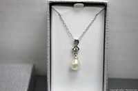 Necklace displayed vertically in a white-lined box, showing pearl pendant with silver decorative element and chain.