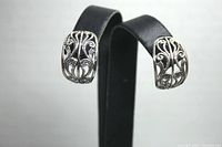 Front angled view of sterling silver cutout lacey earrings displayed on black earring stand, showing intricate scroll design and detailed openwork.