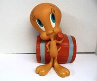 Front view showing Tweety Bird standing with an orange barrel with gray bands behind.