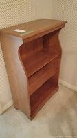 Frontal view of maple wood bookcase showing three shelves and wood grain finish.