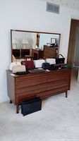 Front view of Gibbard wood dresser with attached mirror and multiple wallet and bag items on top for scale.