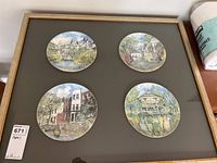 Frontal photo of the four circular illustrated Royal Doulton plates mounted on a dark background inside a wooden frame with glass.