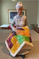Front view of Royal Doulton Eventide figurine showing elderly woman on chair with colorful quilt.
