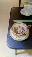 Full view of teacup on saucer showing floral decoration and gilt trim