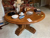 Photo showing round wood table with pedestal base, items on table for staging only.