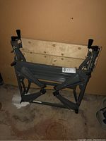 Foldable work table folded against basement wall, showing wooden surface and metal frame with hinges.