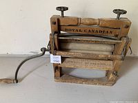 Front view of the antique wooden wash wringer showing 'Royal Canadian' branding and wooden rollers with metal adjustment knobs.