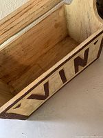 Close-up inside view of the wood box marked 'VIN' showing natural wood interior and painted exterior with brown letters.