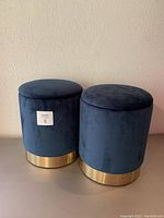 Two blue velvet storage stools side by side showing overall condition and appearance.