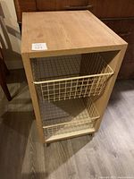 Front angle view of the kitchen cart showing the two cream-colored metal wire pullout baskets inside the light wood frame