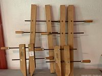 Four wooden bar clamps displayed together, showing size difference and overall condition