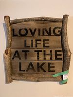 Photo of large wooden wall art with black painted text 'Loving Life at the Lake', framed by natural wood branches.