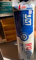 Full shot of unopened package of Johns Manville R-12 fiberglass insulation, showing branding and packaging details.