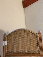 Close-up view of the woven rattan top of the standing mirror frame with finial details.