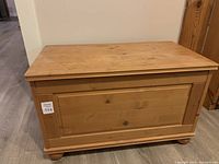 Front view of wooden toy box with visible wood grain and panel front.