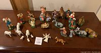 Photo showing entire collection of nativity figurines arranged on a table, including human figures, animals, and angels.