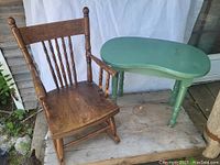 Child's wooden pressback rocker alongside small kidney-shaped green painted table, both placed on wood floor.