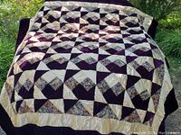 Full view of quilt draped outdoors showing overall geometric star pattern and border
