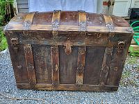Full view of early oak and metal humpback trunk showing front and curved lid with metal fittings