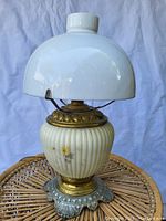 Front view of vintage oil lamp electrified with white ribbed ceramic base, brass detailing, and white glass shade.