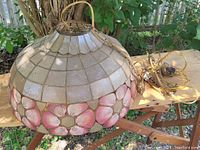 View of the vintage hanging lamp made from capiz shells with pink floral decoration along the bottom edge, showing the wiring and hanging chain.
