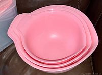 Three pink KitchenAid mixing bowls nested inside each other showing varying sizes and pouring spouts.