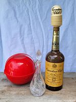 Full view of red plastic picnic set, glass decanter, and Canadian Club bottle with stopper.