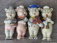 Four vintage 1950s ceramic hand-painted pig musician figurines standing side by side on a flat surface, showing overall condition and details