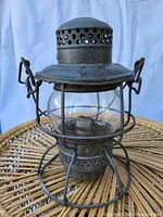 Front view showing the glass globe, metal cage, and top perforations of the lantern.