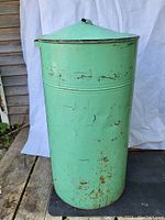 Front angle showing the cylindrical green metal flour tin with scratches, rust spots, and minor dents.