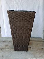 Front view of the tall rectangular planter showing textured brown plastic wicker weave.