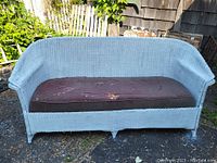 Front view of 1930s Haywood Wakefield wicker couch with blue painted wicker frame and brown cushion showing wear.