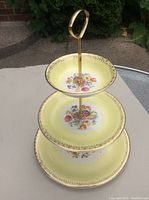 Full view of the 3-tier vintage cake/candy server showing the yellow floral design and gold trim on all plates.