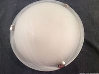 Front view of one round ceiling light fixture showing frosted glass cover with three metal clips around the edge.