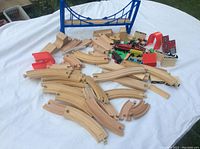 Full overview of train and race set pieces spread on a table showing wooden tracks, blue bridge, and various cars and accessories.