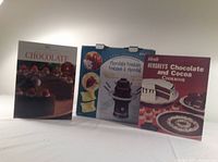 Three chocolate-related items: an electric chocolate fountain in box and two chocolate-themed cookbooks.