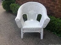 Front view of the white wicker chair showing woven seat, armrests and backrest