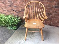 Front view of the vintage Windsor style wooden armchair showing curved back, spindled supports and solid contoured seat.