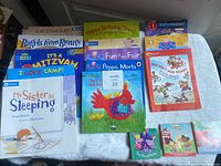 Photo showing a collection of colorful children's book covers including Peppa Pig titles, religious themed books, and other storybooks arranged on a white surface.