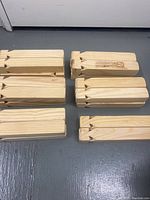 Top-down view of several solid wood train whistles arranged on floor showing natural wood grain and carved whistle ends.